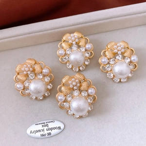 Macro shot of vintage golden flower earrings with white pearls and sparkling rhinestones