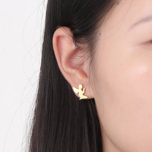 Close-up of a gold angel stud earring worn by a model, showing fine metallic details