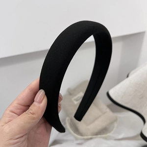 Close-up of a wide black padded fabric headband with a premium minimalist French texture