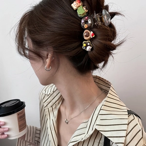 Detailed view of a dark brown hair claw clip with cute cartoon bear and donut charms