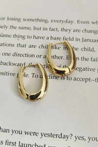 Polished golden U-shaped earrings on artistic white paper background with text