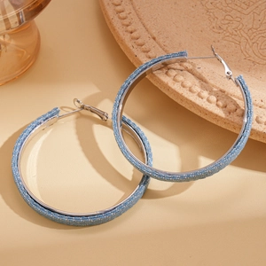 Close-up of geometric hoop earrings featuring blue denim fabric and silver metal frame