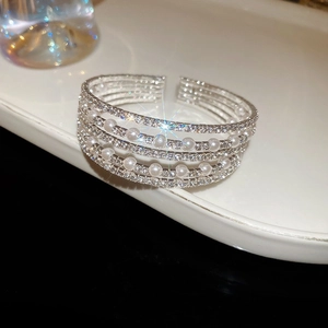 Vue détaillée d'un bracelet ouvert multi-rangs argenté avec perles et strass sur un plateau blanc