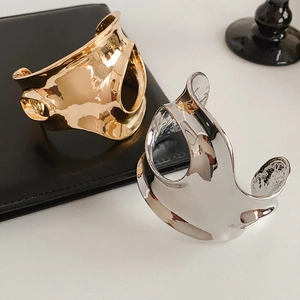 Détail de bracelets géométriques évidés en finition or et argent sur cuir noir