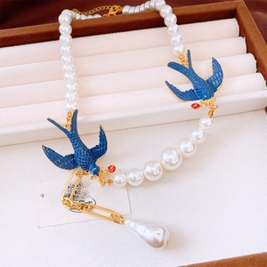 Detail of pearl necklace with blue enamel swallows and large baroque pearl pendant
