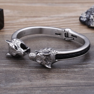 Detail of vintage wolf head stainless steel bangle with black braided leather texture
