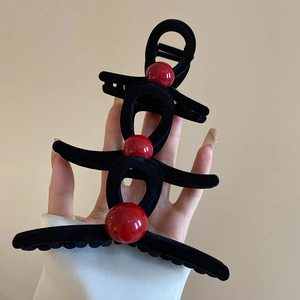 Three sizes of black flocked hair claws with vibrant red bead accents held in hand
