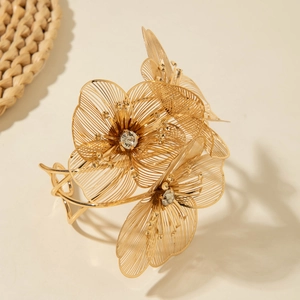 Exaggerated gold open cuff bracelet with hollow floral design and sparkling crystals