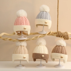 Winter knit baby earflap hats with pom-poms and cable knit patterns in various colors