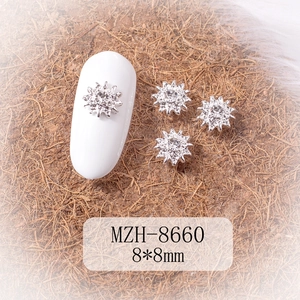 Detailed view of silver snowflake nail charms with crystal rhinestones on a nail model