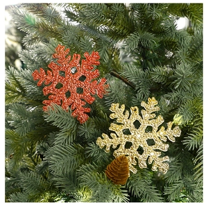 Nahaufnahme roter und goldener Schneeflocken-Anhänger an einem grünen Weihnachtsbaum