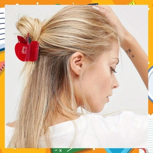 Détail d'une pince à cheveux en acrylique rouge en forme de pomme sur cheveux