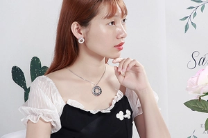 Detail of silver MOM heart necklace and matching earrings worn by a model in natural light
