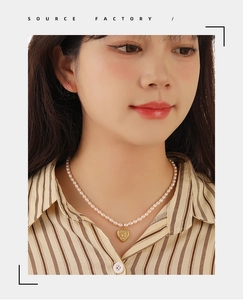Detail of elegant pearl necklace featuring a vintage gold embossed heart pendant