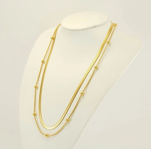 Nahaufnahme der goldenen zweilagigen Halskette mit Schlangenkette und Perlendetails
