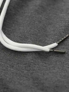 Detail of white braided drawstring with matte grey metal tips on textured grey fabric