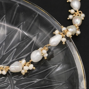 Baroque pearl necklace with irregular natural beads and gold accents on a glass plate
