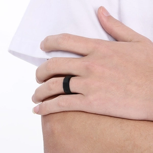 Detailed view of an 8mm black brushed faceted stainless steel ring on a male finger