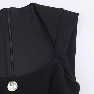 Detail shot of a black romper featuring an invisible zipper and crystal jewelry button
