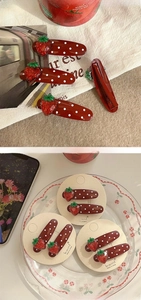 Detail of red strawberry hair clips with white polka dots on a metal duckbill base