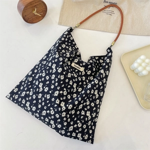 Vue détaillée du sac cabas en toile fleurie avec poignées en cuir marron et étiquette
