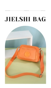 Detail of lightweight orange nylon crossbody bag with circular Jielshi logo branding