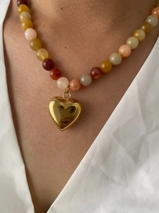 Detail of colorful natural stone beaded necklace with a polished gold heart pendant
