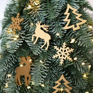 Laser-cut wooden Christmas ornaments with golden elk and snowflake hanging on pine tree