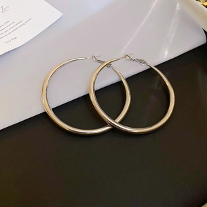 Detailed view of silver geometric hoop earrings with twisted design on white background
