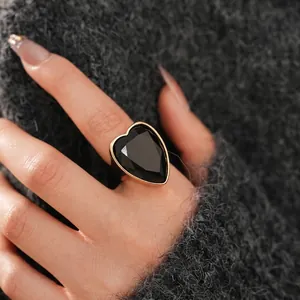 Luxurious wide gold band ring featuring a large faceted black heart stone on a hand
