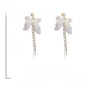 Détail de boucles d'oreilles nœuds en tulle blanc avec longs glands en perles de nacre