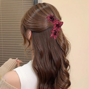 Detail of elegant wine red flower hair claw clip styling a ponytail on a female model