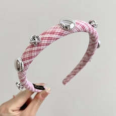 Detail view of a knotted pink and white checkered fabric headband with silver metal accents