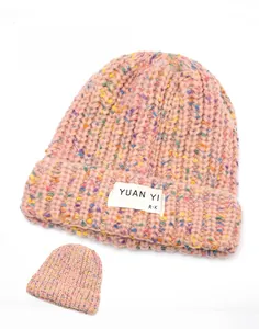 Detail of chunky knit mixed-yarn beanie featuring a branded fabric label on white background
