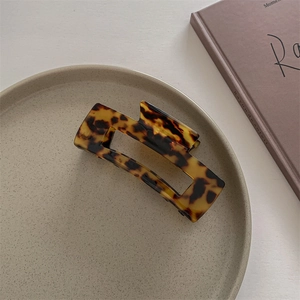 Detail of tortoise shell acetate claw clip on aesthetic beige plate and vintage book