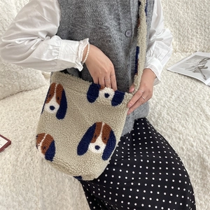 Detail of soft plush shoulder bag with cute cartoon dog patterns on fuzzy cream texture