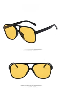 Close-up of glossy black double bridge pilot sunglasses with vintage yellow lenses