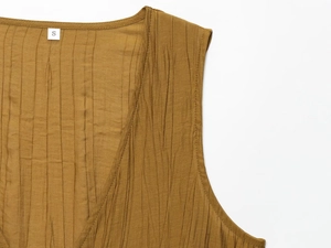 Detail shot of ginger yellow sleeveless top neck and pleated texture fabric for women