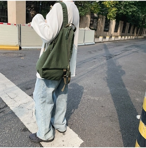 Street style shot of a casual military green canvas backpack on a male model outdoors