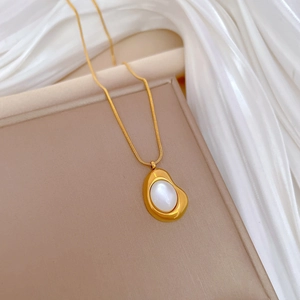 Close-up of a gold titanium steel necklace featuring a cat-eye stone pendant on a beige stand
