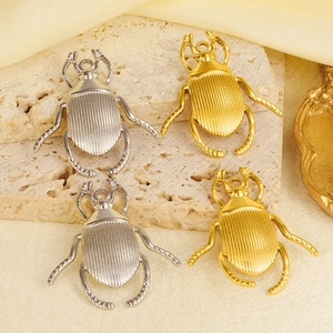 Detailed view of gold and silver beetle charms on stone for jewelry making