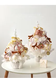 Detailed close-up of two white mini Christmas trees decorated with bows and Noel ornaments