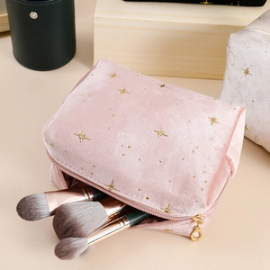 Close-up of pink velvet cosmetic bag with gold star embroidery and zipper tassel