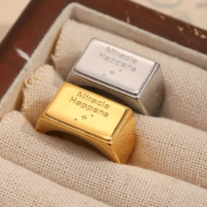 Dettaglio di anelli a sigillo quadrati con incisione Miracle Happens in oro e argento