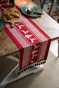 Close-up of red and white knitted Christmas table runner with reindeer and tassels