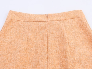 Gros plan sur la fermeture éclair invisible d'une mini-jupe orange en tweed chic