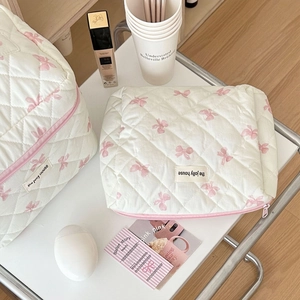 Detail of white quilted toiletry bag set with pink bows and elegant stitching
