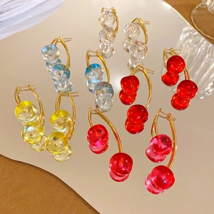Macro view of cherry-shaped beaded drop earrings with golden metal hooks in multiple colors