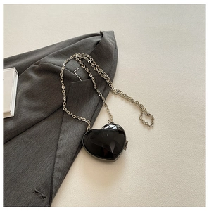 Detail of a black heart-shaped mini evening bag with geometric faceted design and silver chain