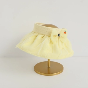 Detail of a light yellow open top sun hat with a chiffon bow and orange pin decor
